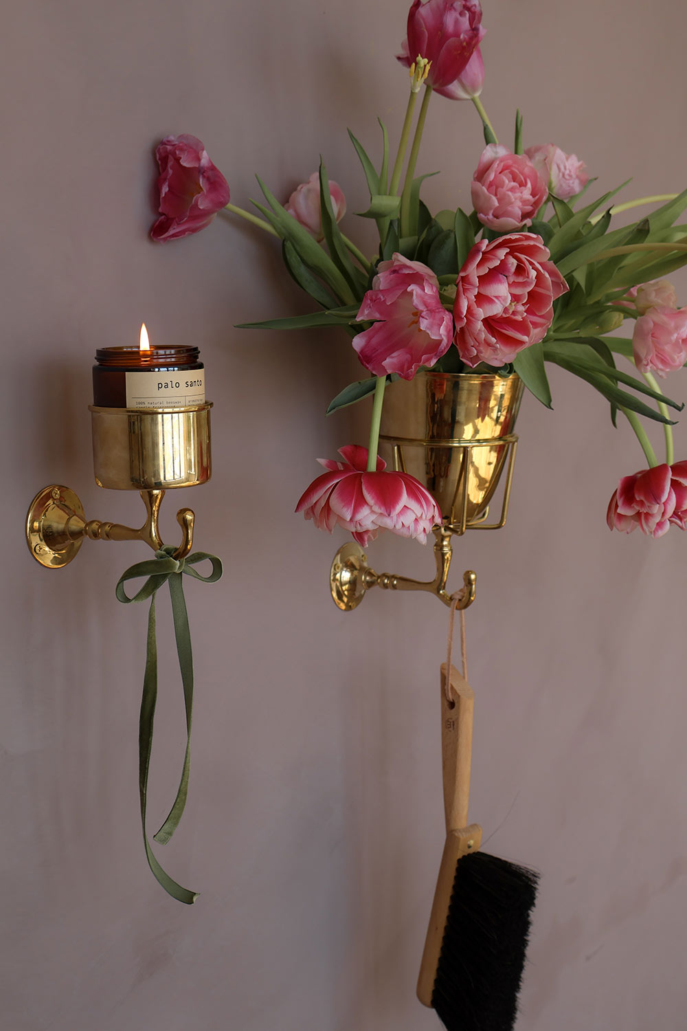 Decorative wall sconce with a candle and pink flowers against a plain background